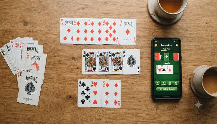 Rummy Apps Beginner arranging playing cards into rummy sequences next to a rummy app on a smartphone